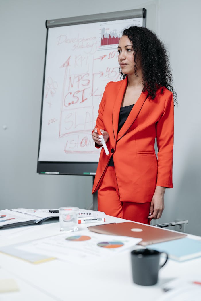 Confident businesswoman stands by flipchart during meeting.